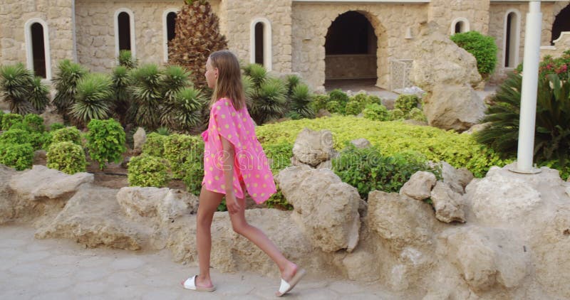 μοντέρνο κορίτσι που περπατά με πέτρες και φυτά σε ένα ιστορικό πολυτελές ξενοδοχείο