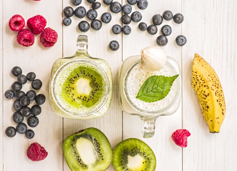 Μπανάνα και ακτινίδιο milkshakes στα βάζα κτιστών με creme και τις διακοσμήσεις σε τοπ και διακοσμημένος με τα βακκίνια, μπανάνες στοκ φωτογραφία με δικαίωμα ελεύθερης χρήσης Μπανάνα και ακτινίδιο milkshakes στα βάζα κτιστών με creme και τις διακοσμήσεις σε τοπ και διακοσμημένος με τα βακκίνια, μπανάνες στοκ φωτογραφία με δικαίωμα ελεύθερης χρήσης