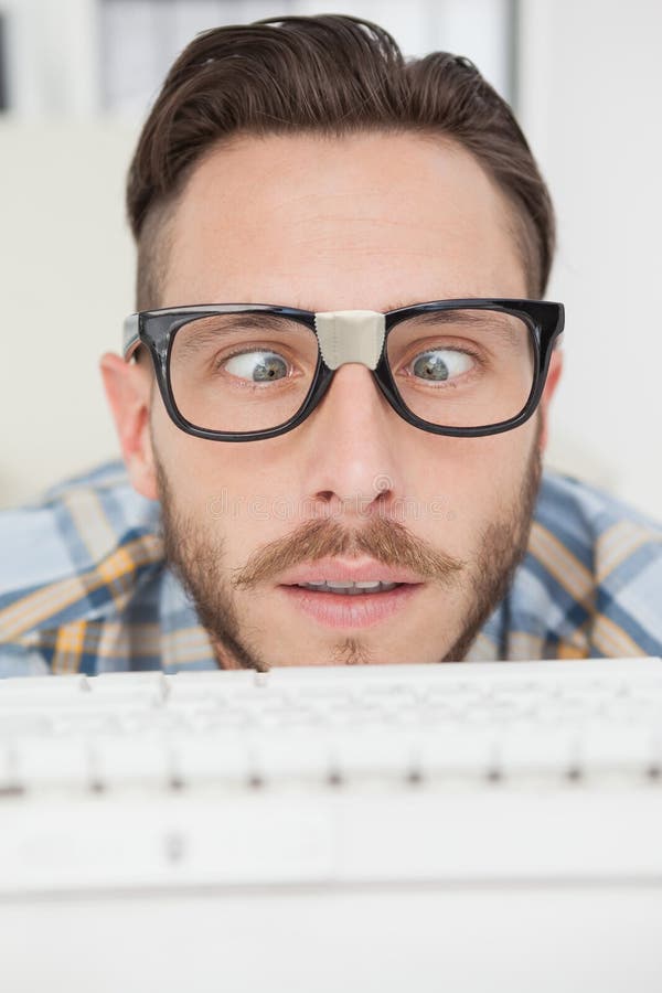 Μπερδεμένος nerdy επιχειρηματίας που εργάζεται στον υπολογιστή στοκ εικόνες