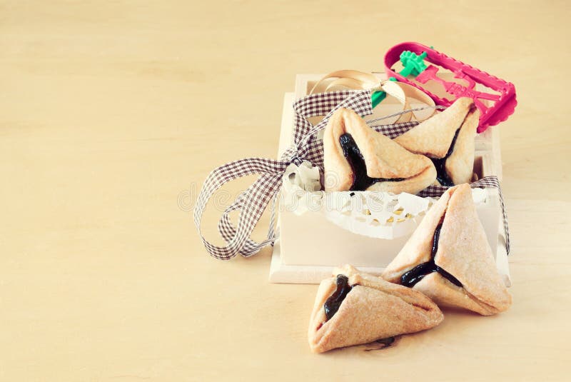Μπισκότα ή hamans αυτιά Hamantaschen για τον εορτασμό Purim στο ξύλινα κιβώτιο και Noisemaker στοκ φωτογραφίες με δικαίωμα ελεύθερης χρήσης