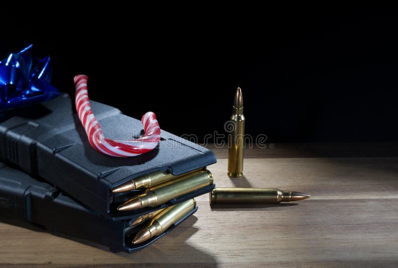 Copy space on the black background behind two loaded AR-15 magazines with a blue bow and candy cane atop. Copy space on the black background behind two loaded AR-15 magazines with a blue bow and candy cane atop