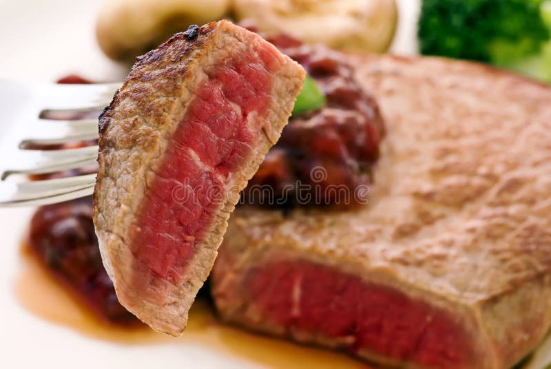 Medium grilled steak piece as closeup on fork. Medium grilled steak piece as closeup on fork.