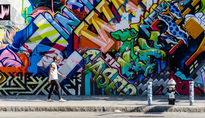 BROOKLYN, NYC, US, October 1 2013: Street art in Brooklyn. Hipster male walking next to a wall of graffiti in Brooklyn, New York, US. BROOKLYN, NYC, US, October 1 2013: Street art in Brooklyn. Hipster male walking next to a wall of graffiti in Brooklyn, New York, US.