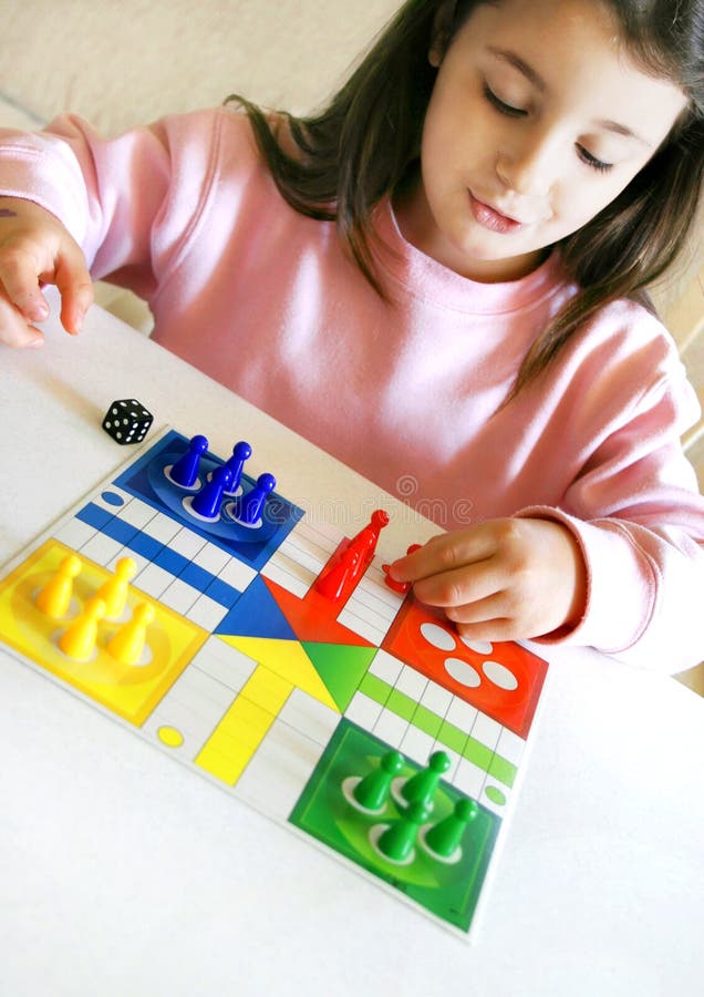 Little six year old girl alone at home, smiles arranging her pawns on the table for a game. Little six year old girl alone at home, smiles arranging her pawns on the table for a game