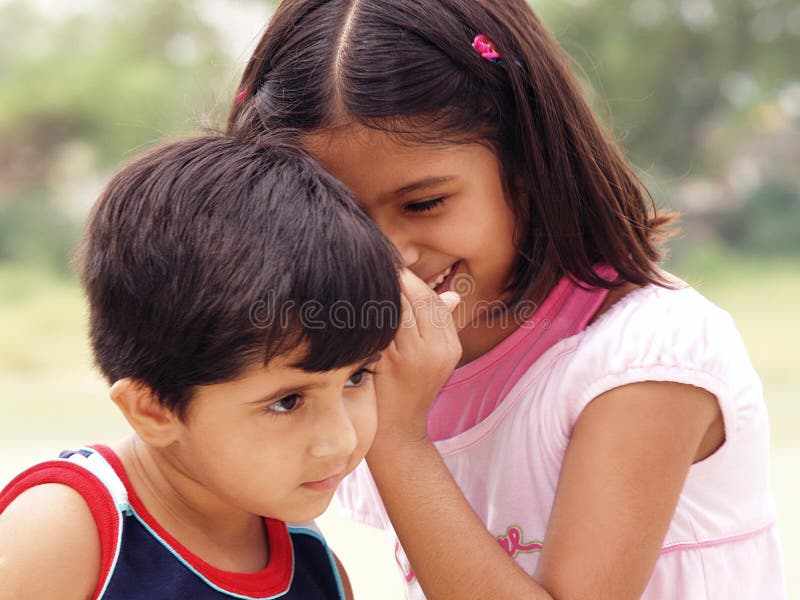 A cute portrait of an older sister whispering and sharing a secret in the ear of her younger sister. A cute portrait of an older sister whispering and sharing a secret in the ear of her younger sister.