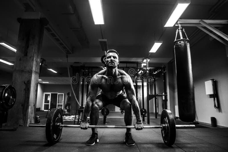 Strong muscular man at a crossfit gym lifting a barbell. Strong muscular man at a crossfit gym lifting a barbell.