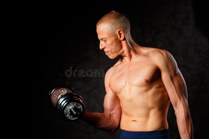 Μυϊκός τύπος bodybuilder που κάνει τις ασκήσεις με τον αλτήρα πέρα από το σκοτεινό υπόβαθρο στοκ εικόνες Μυϊκός τύπος bodybuilder που κάνει τις ασκήσεις με τον αλτήρα πέρα από το σκοτεινό υπόβαθρο στοκ εικόνες