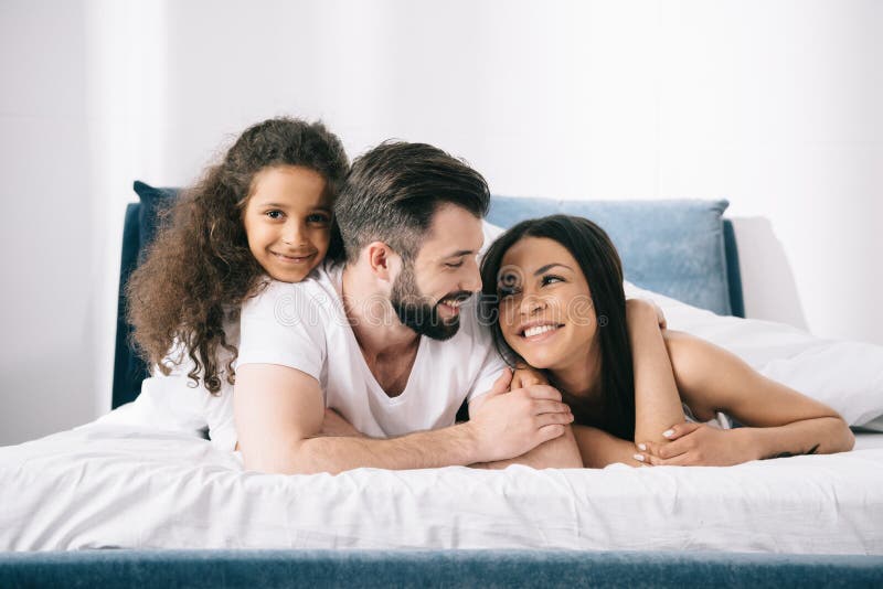 Νέα multiethnic οικογένεια με ένα παιδί που βρίσκεται μαζί στο κρεβάτι στοκ φωτογραφίες με δικαίωμα ελεύθερης χρήσης Νέα multiethnic οικογένεια με ένα παιδί που βρίσκεται μαζί στο κρεβάτι στοκ φωτογραφίες με δικαίωμα ελεύθερης χρήσης