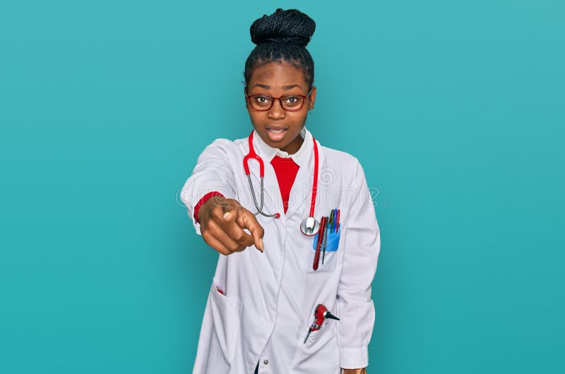 Young african american woman wearing doctor uniform and stethoscope pointing displeased and frustrated to the camera, angry and furious with you. Young african american woman wearing doctor uniform and stethoscope pointing displeased and frustrated to the camera, angry and furious with you