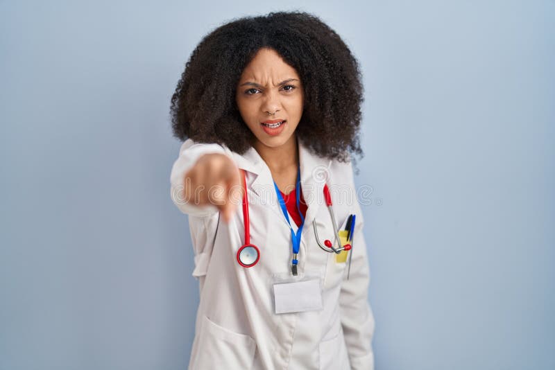 Young african american woman wearing doctor uniform and stethoscope pointing displeased and frustrated to the camera, angry and furious with you. Young african american woman wearing doctor uniform and stethoscope pointing displeased and frustrated to the camera, angry and furious with you