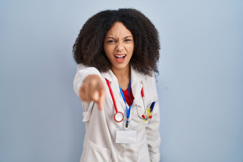 Young african american woman wearing doctor uniform and stethoscope pointing displeased and frustrated to the camera, angry and furious with you. Young african american woman wearing doctor uniform and stethoscope pointing displeased and frustrated to the camera, angry and furious with you