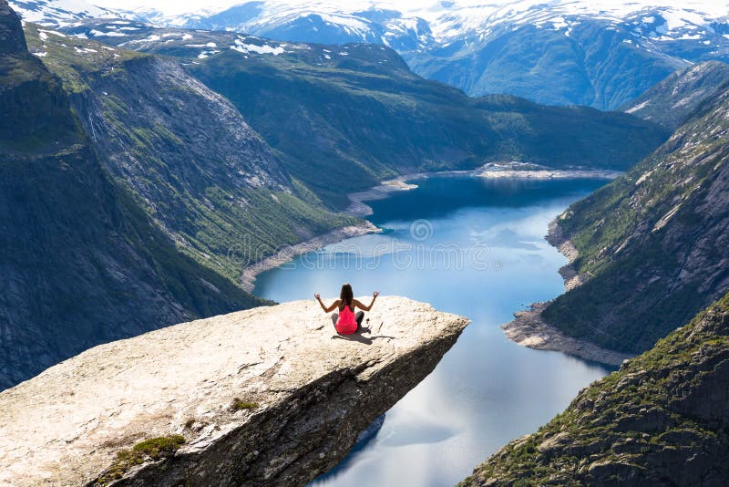 Νέα γυναίκα relaxon Trolltunga Το ευτυχές κορίτσι απολαμβάνει την όμορφη λίμνη και τον καλό καιρό στη Νορβηγία στοκ φωτογραφία Νέα γυναίκα relaxon Trolltunga Το ευτυχές κορίτσι απολαμβάνει την όμορφη λίμνη και τον καλό καιρό στη Νορβηγία στοκ φωτογραφία