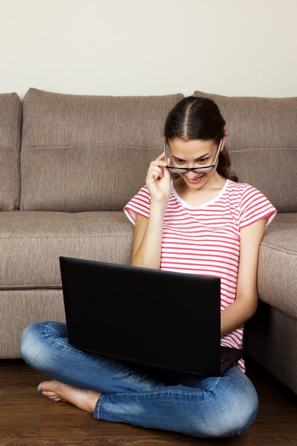 Νέα γυναίκα με τη συνεδρίαση lap-top στον καναπέ στοκ εικόνες με δικαίωμα ελεύθερης χρήσης Νέα γυναίκα με τη συνεδρίαση lap-top στον καναπέ στοκ εικόνες με δικαίωμα ελεύθερης χρήσης