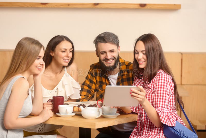 Νέα γυναίκα με το PC ταμπλετών που παρουσιάζει κάτι για τους φίλους της στον καφέ στοκ φωτογραφία Νέα γυναίκα με το PC ταμπλετών που παρουσιάζει κάτι για τους φίλους της στον καφέ στοκ φωτογραφία
