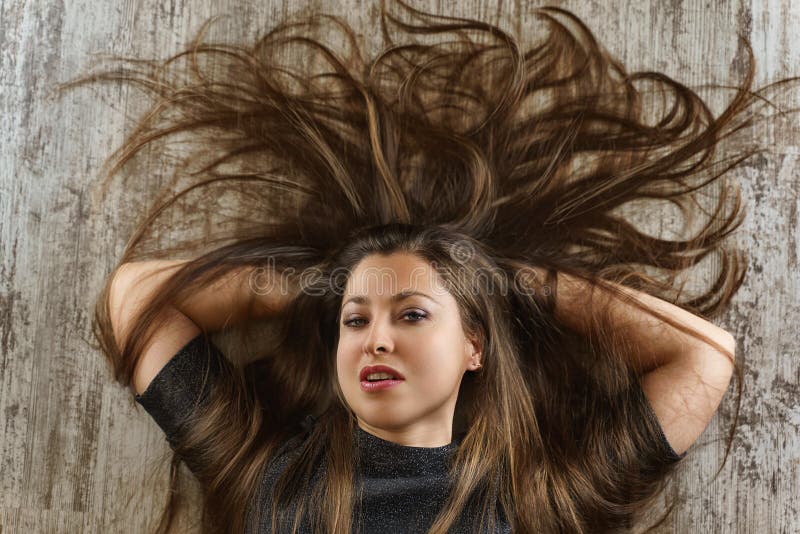 Νέα γυναίκα με το όμορφο hairstyle που βρίσκεται στο πάτωμα r στοκ εικόνα με δικαίωμα ελεύθερης χρήσης Νέα γυναίκα με το όμορφο hairstyle που βρίσκεται στο πάτωμα r στοκ εικόνα με δικαίωμα ελεύθερης χρήσης
