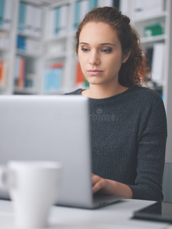 Νέα γυναίκα που εργάζεται με ένα lap-top στοκ εικόνα Νέα γυναίκα που εργάζεται με ένα lap-top στοκ εικόνα