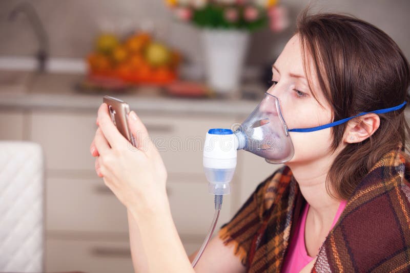 Νέα γυναίκα που κάνει την εισπνοή με nebulizer στο σπίτι στοκ φωτογραφίες Νέα γυναίκα που κάνει την εισπνοή με nebulizer στο σπίτι στοκ φωτογραφίες