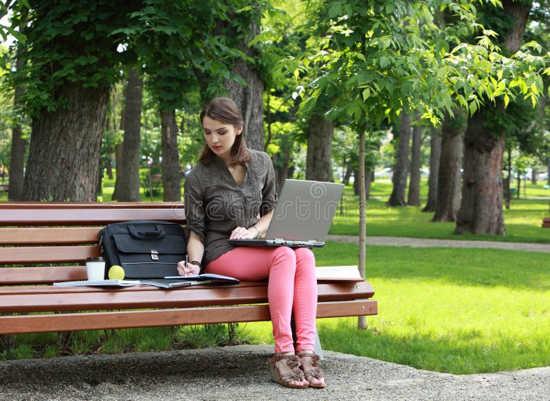 Νέα γυναίκα που μελετά σε ένα πάρκο