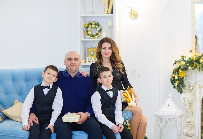 Νέα ευτυχής συνεδρίαση μητέρων και πατέρων στον καναπέ με τους γιους στο διακοσμημένο δωμάτιο για τις διακοπές Χριστουγέννων στοκ φωτογραφίες με δικαίωμα ελεύθερης χρήσης Νέα ευτυχής συνεδρίαση μητέρων και πατέρων στον καναπέ με τους γιους στο διακοσμημένο δωμάτιο για τις διακοπές Χριστουγέννων στοκ φωτογραφίες με δικαίωμα ελεύθερης χρήσης