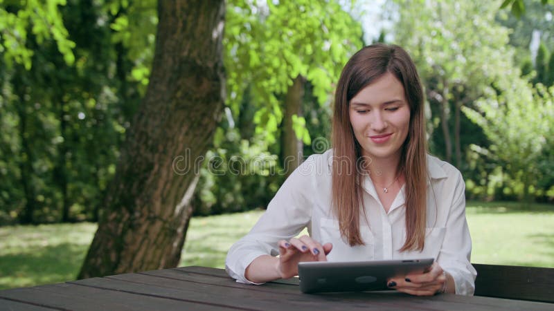 Νέα κυρία που χρησιμοποιεί ένα ipad στο πάρκο στοκ φωτογραφία με δικαίωμα ελεύθερης χρήσης Νέα κυρία που χρησιμοποιεί ένα ipad στο πάρκο στοκ φωτογραφία με δικαίωμα ελεύθερης χρήσης