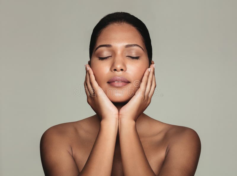 Portrait of young natural beauty with beautiful skin. Female touching her fresh clean and clear face against grey background. Portrait of young natural beauty with beautiful skin. Female touching her fresh clean and clear face against grey background.