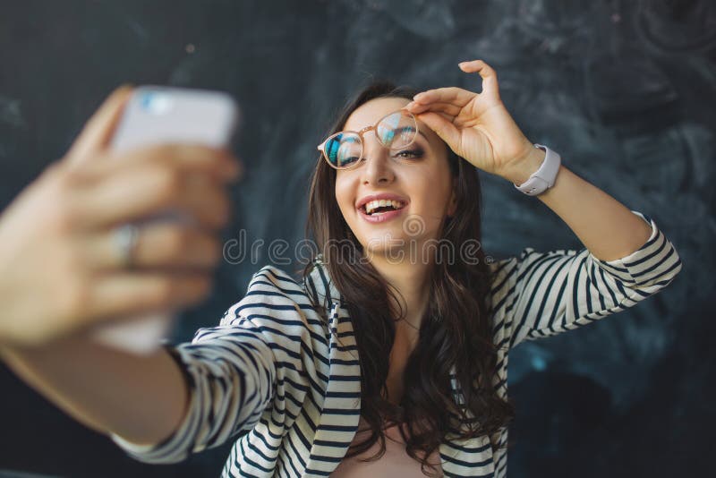 Νέα όμορφη γυναίκα με το smartphone στο χέρι της που παίρνει την εικόνα στοκ εικόνες Νέα όμορφη γυναίκα με το smartphone στο χέρι της που παίρνει την εικόνα στοκ εικόνες