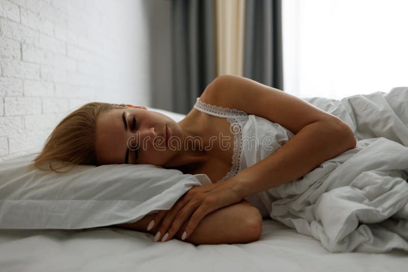 Νέα όμορφη γυναίκα που κοιμάται στο πλάι σε ζεστό κρεβάτι