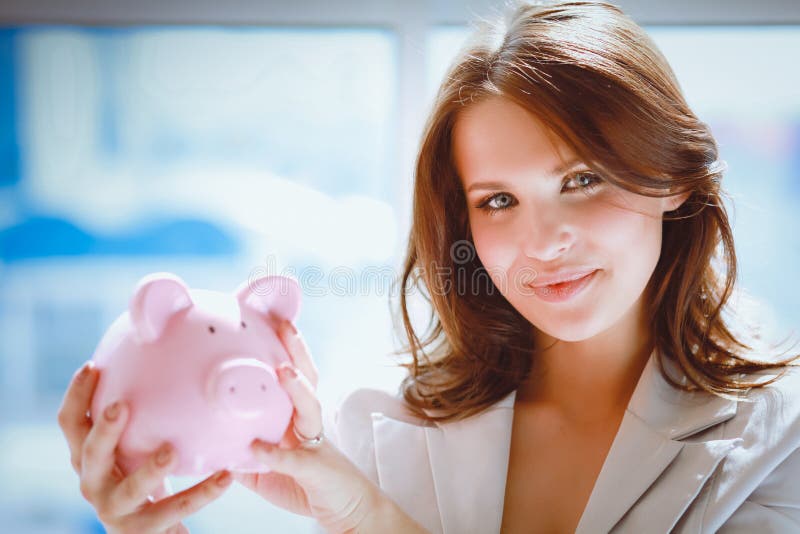 Νέα όμορφη γυναίκα που στέκεται με το piggy κιβώτιο χρημάτων τραπεζών, που απομονώνεται στο άσπρο υπόβαθρο στοκ φωτογραφία Νέα όμορφη γυναίκα που στέκεται με το piggy κιβώτιο χρημάτων τραπεζών, που απομονώνεται στο άσπρο υπόβαθρο στοκ φωτογραφία