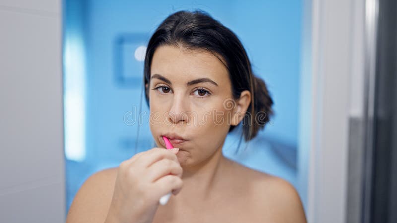 νέα όμορφη ισπανόφωνη γυναίκα βουρτσίζει δόντια στο μπάνιο στοκ εικόνες