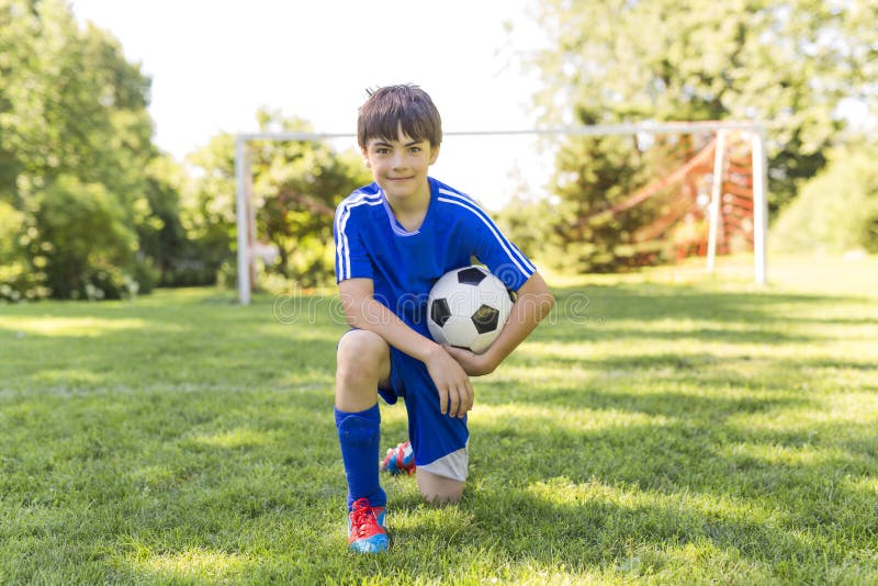 Νέο αγόρι με τη σφαίρα ποδοσφαίρου σε έναν αθλητισμό ομοιόμορφο