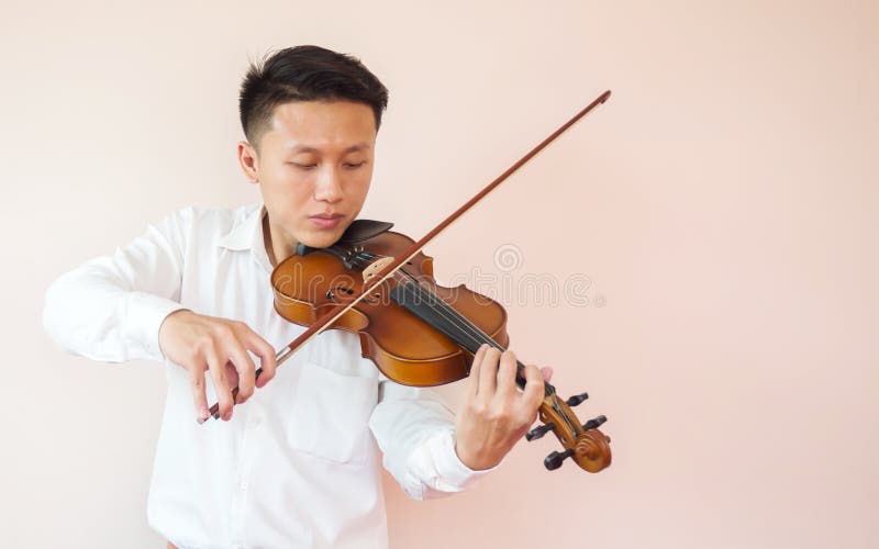 Young Asian man play violin. Classical music instrument. String equipment. Art and music portrait background. Copy space and white in pink shade background. Young Asian man play violin. Classical music instrument. String equipment. Art and music portrait background. Copy space and white in pink shade background.