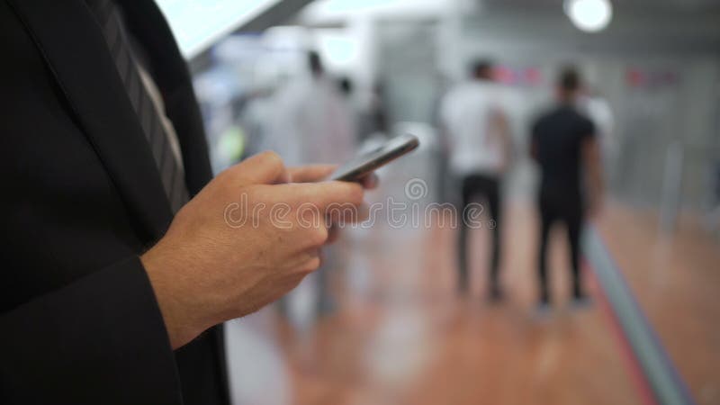 Νέο επιχειρηματιών στο smartphone στεμένος στη σειρά αναμονής, σύγχρονες συσκευές