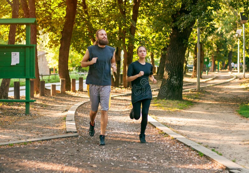 Νέο ζεύγος που τρέχει στη jogging διαδρομή μέσω του δάσους στοκ εικόνες Νέο ζεύγος που τρέχει στη jogging διαδρομή μέσω του δάσους στοκ εικόνες