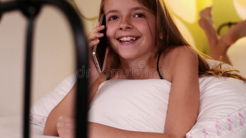 Νέο κορίτσι που χρησιμοποιεί το smartphone που μιλά στο κρεβάτι