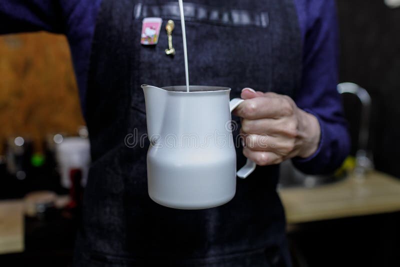 Νέο χύνοντας γάλα κοριτσιών barista στο pinscher στοκ εικόνες Νέο χύνοντας γάλα κοριτσιών barista στο pinscher στοκ εικόνες