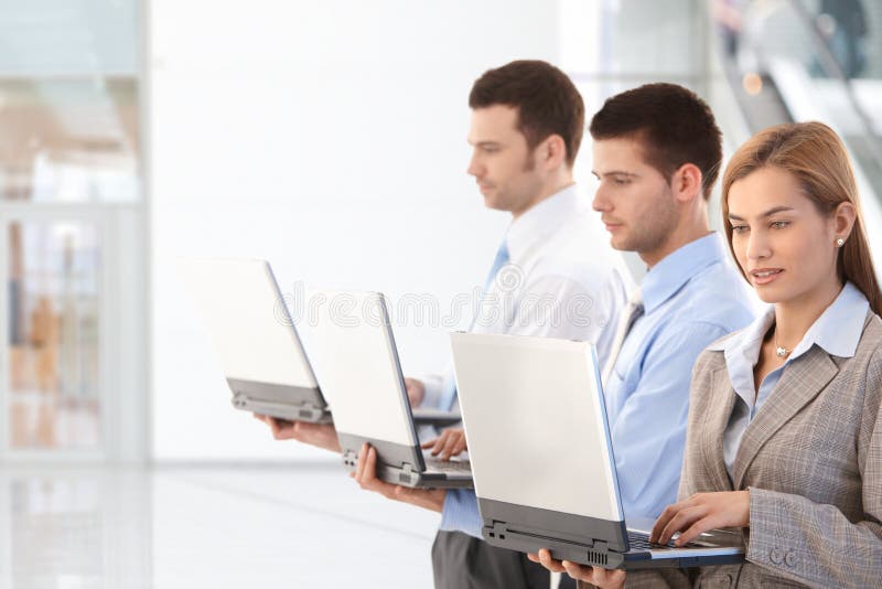 Young business professionals working on laptop in office lobby. Young business professionals working on laptop in office lobby.