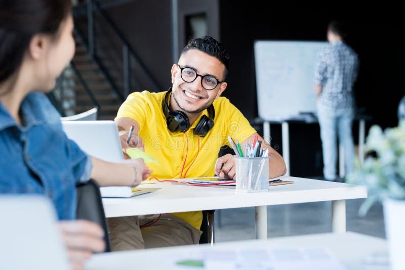 Portrait of creative young Middle-Eastern men wearing glasses working in open space office of IT developers team, copy space. Portrait of creative young Middle-Eastern men wearing glasses working in open space office of IT developers team, copy space