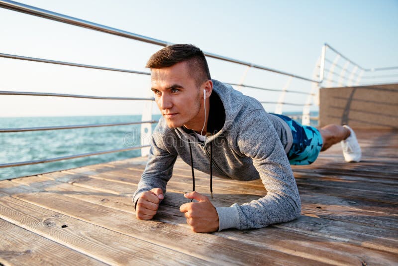 Νέος αθλητικός τύπος στη θέση σανίδων, workout στην αποβάθρα στοκ φωτογραφία με δικαίωμα ελεύθερης χρήσης Νέος αθλητικός τύπος στη θέση σανίδων, workout στην αποβάθρα στοκ φωτογραφία με δικαίωμα ελεύθερης χρήσης