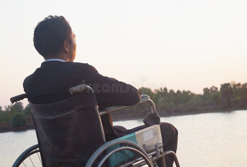 νέος ανάπηρος με επιτόπου οπισθοφυλακή που κάθεται σε αναπηρική καρέκλα στοκ εικόνες