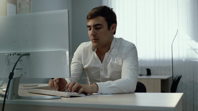 Νέος επιχειρηματίας χρησιμοποιώντας τον υπολογιστή γραφείου και γράφοντας κάτω τις πληροφορίες στο σημειωματάριο απόθεμα βίντεο
