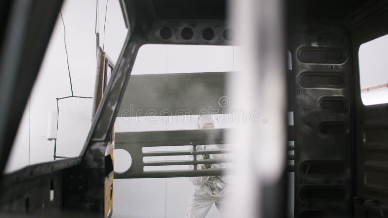 Νέος εργαζόμενος στην άσπρη ομοιόμορφη καμπίνα φορτηγών χρωμάτων με τη μηχανή ψεκαστήρων απόθεμα βίντεο