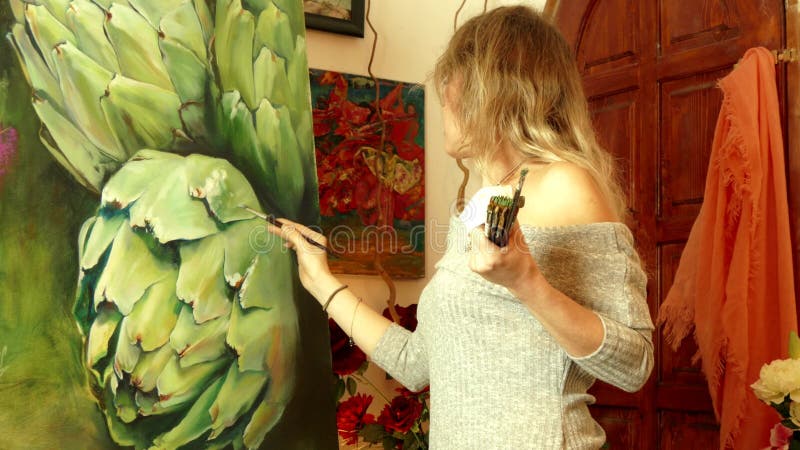 Νέος καλλιτέχνης γυναικών που εργάζεται σε ένα στούντιο που χρωματίζει μια αγκινάρα