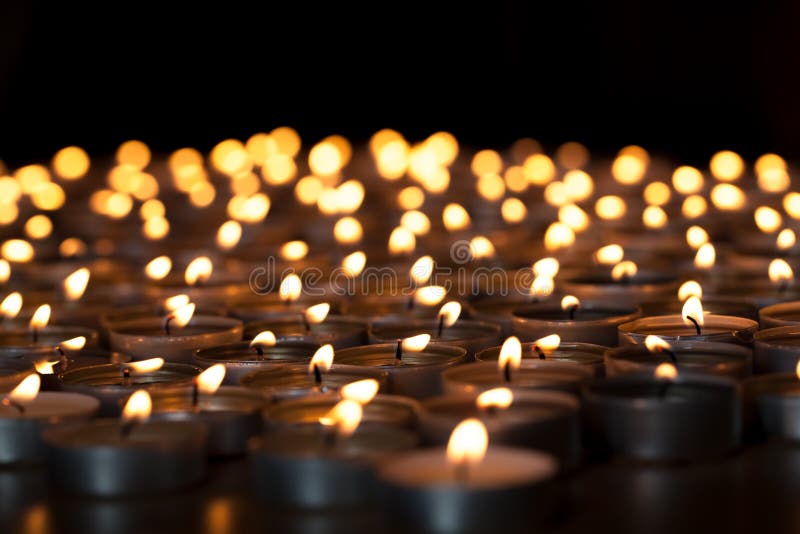 Flaming candles. Spiritual image of tealights providing sacred light. Romantic candlelight at night. A spread of lit wax candles against black background with copy space. Flaming candles. Spiritual image of tealights providing sacred light. Romantic candlelight at night. A spread of lit wax candles against black background with copy space.