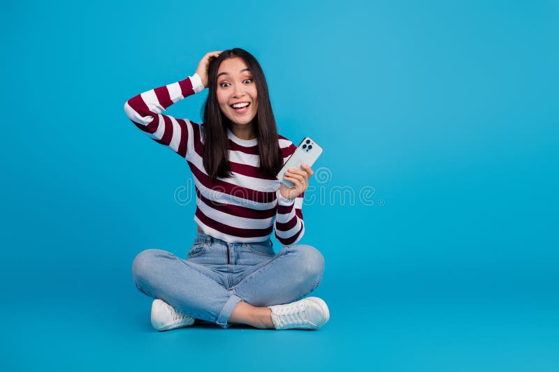 Νεαρή γυναίκα με smartphone που χαμογελάει σε μπλε φόντο στοκ φωτογραφία με δικαίωμα ελεύθερης χρήσης