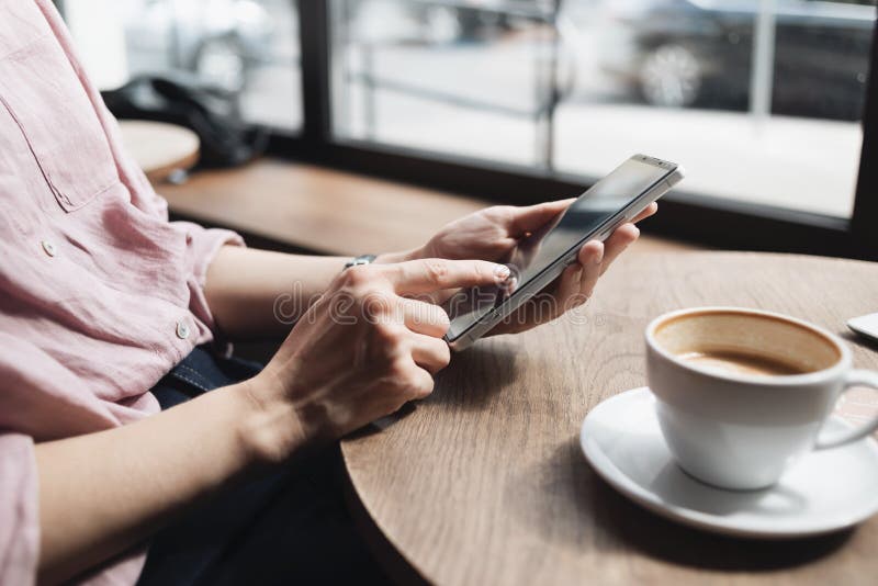 νεαρή γυναίκα που χρησιμοποιεί smartphone στο καφέ. φοιτήτρια στέλνει μηνύματα στο κινητό στο καφενείο. οικιακή εργασία επικοινωνί στοκ φωτογραφίες