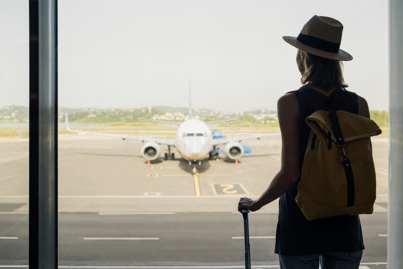 νεαρή γυναίκα στο αεροδρόμιο κοιτάζοντας μέσα από το παράθυρο τα αεροπλάνα ταξιδεύει τουριστικά ταξίδια διακοπές και ενεργό τρόπο στοκ φωτογραφία με δικαίωμα ελεύθερης χρήσης