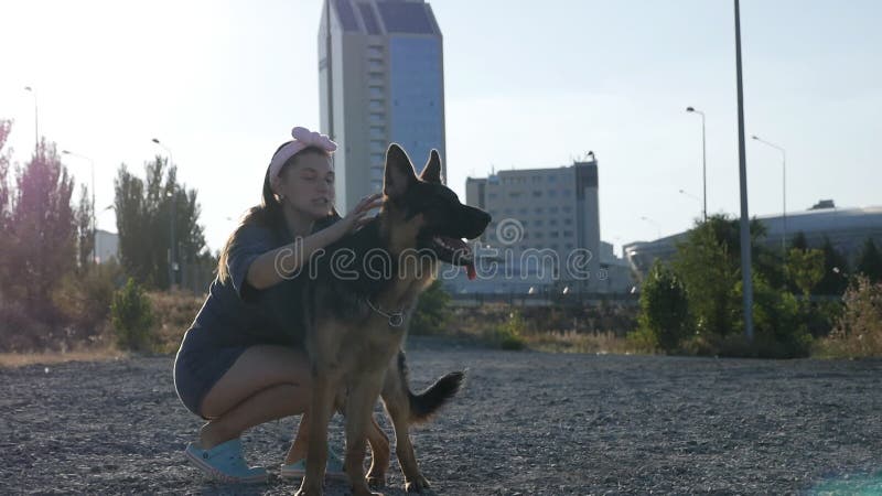 νεαρή γυναίκα στο δρόμο με τον γερμανό ποιμενό της. γυναίκα σε βόλτα με το σκύλο της την κυριακή