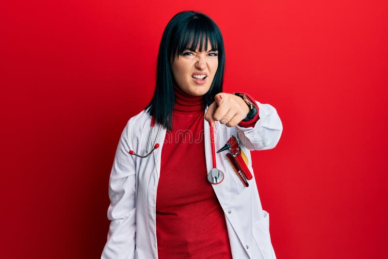 Young hispanic woman wearing doctor uniform and stethoscope pointing displeased and frustrated to the camera, angry and furious with you. Young hispanic woman wearing doctor uniform and stethoscope pointing displeased and frustrated to the camera, angry and furious with you