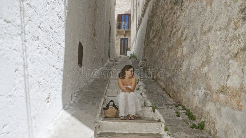 Νεαρή ισπανόφωνη στην παλιά πούλια της πόλης του Κοστούνιτσα Ιταλία κάθεται σε σκάλες σε ένα στενό δρομάκι με μια γαλήνια έκφραση στοκ εικόνα με δικαίωμα ελεύθερης χρήσης