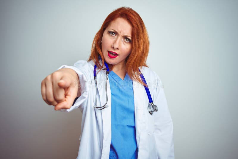 Young redhead doctor woman using stethoscope over white isolated background pointing displeased and frustrated to the camera, angry and furious with you. Young redhead doctor woman using stethoscope over white isolated background pointing displeased and frustrated to the camera, angry and furious with you